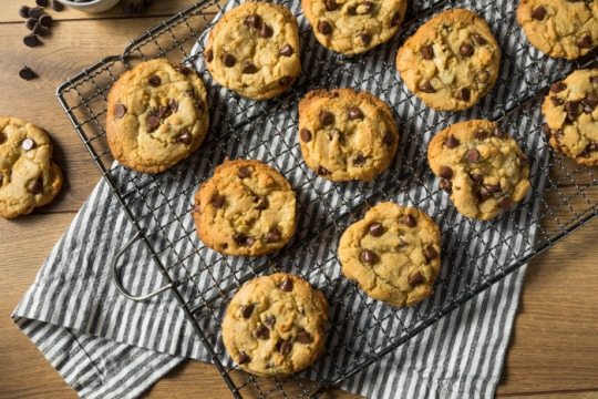 Cooling rack full of chocolate chip cookies on a wooden counter